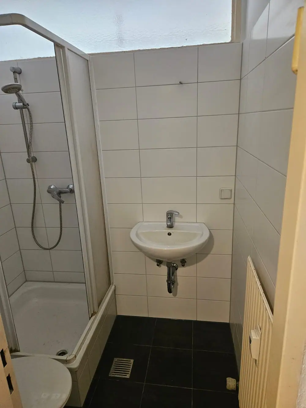Kleines Bad mit Dusche, Waschbecken und Heizkörper nach der Renovierung
