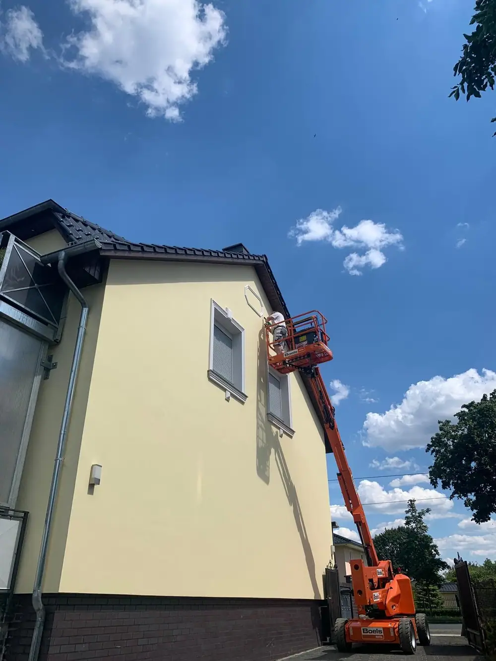 Frisch gestrichene gelbe Altbaufassade mit Hubsteiger davor