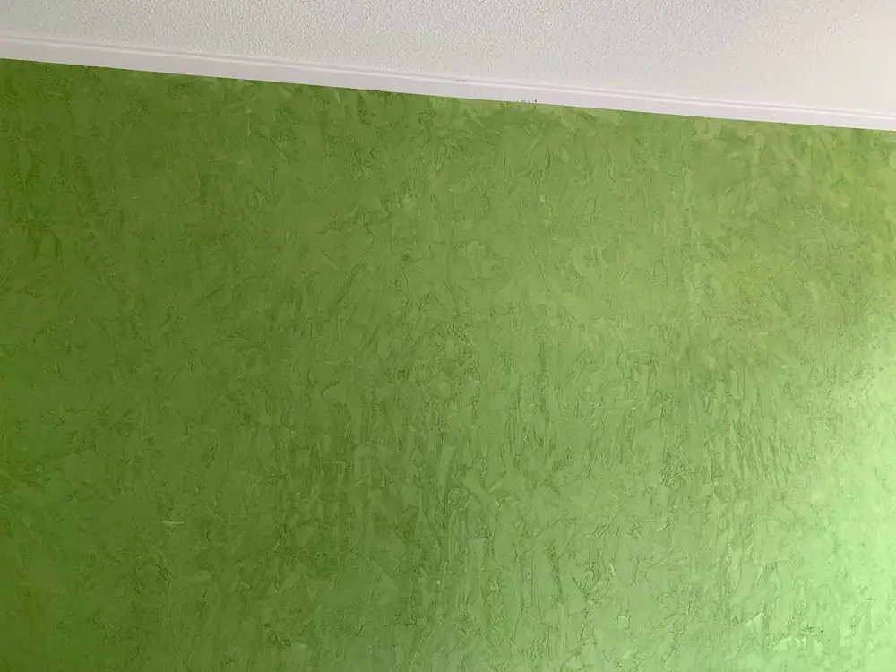 Nahaufnahme einer grünen Wand mit feiner Wischstruktur