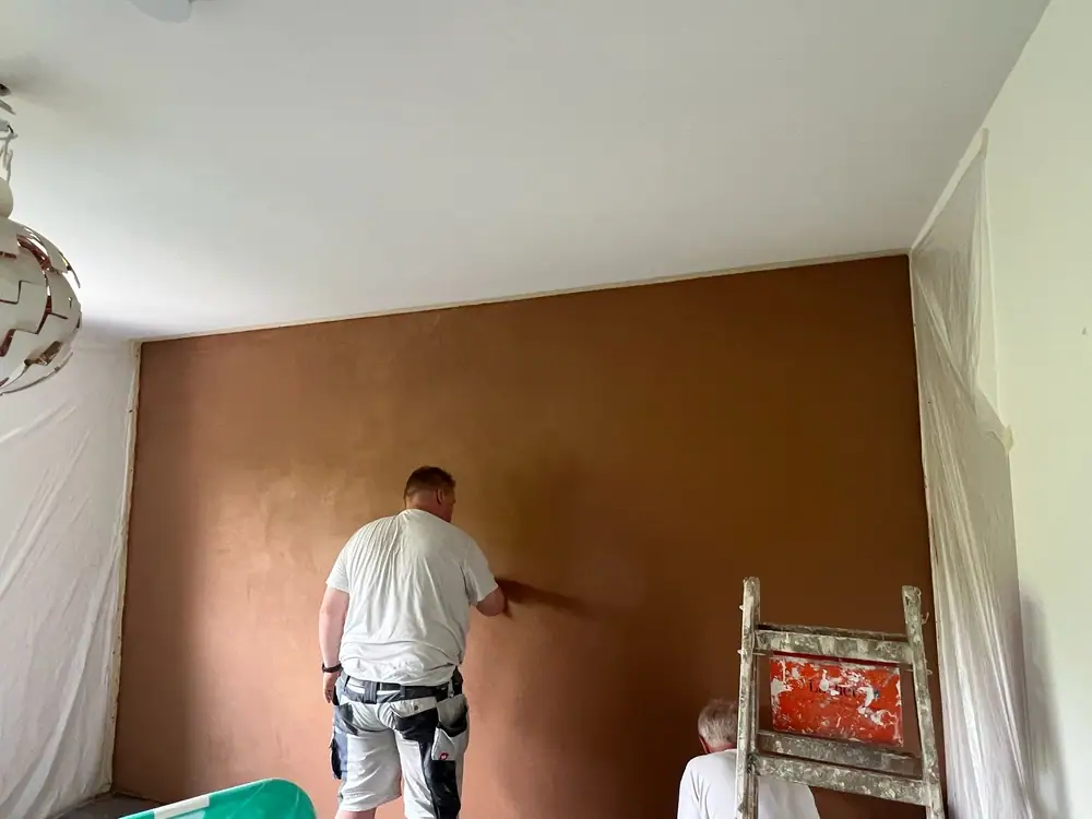 Maler glättet eine braune Spachtelwand von Hand